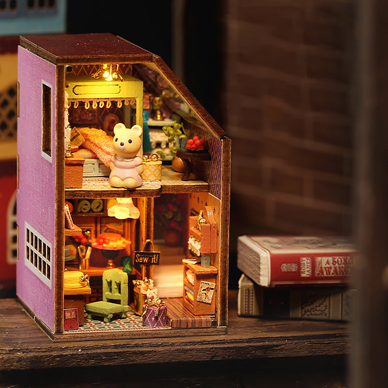 Pink miniature dollhouse model with toy bus in scene